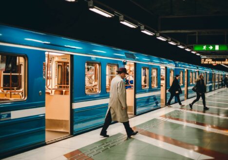 metrostation met blauwe metro en man in lange jas die uitstapt